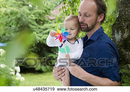 Father and baby daughter playing with pinwheel in garden View Large Photo Image Stock Photo - Father and baby daughter playing with pinwheel in garden. Fotosearch