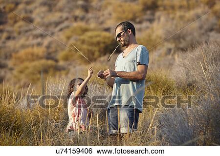 Stock Photograph - Father and daughter playing with long grass, Almeria, Andalusia, Spain. Fotosearch