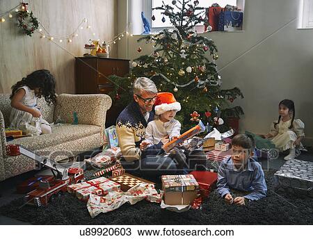 Father and four children opening christmas gifts in sitting room View Large Photo Image Stock Image - Father and four children opening christmas gifts in sitting room. Fotosearch