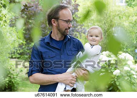 Father carrying baby daughter in garden View Large Photo Image Stock Image - Father carrying baby daughter in garden. Fotosearch