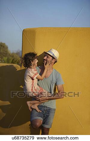 Father holding daughter, leaning against wall, Costa Brava, Catalonia, Spain View Large Photo Image Stock Photo - Father holding daughter, leaning against wall, Costa Brava, Catalonia, Spain. Fotosearch