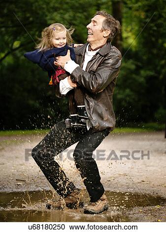 Father holding daughter, splashing in puddle View Large Photo Image Stock Image - Father holding daughter, splashing in puddle. Fotosearch