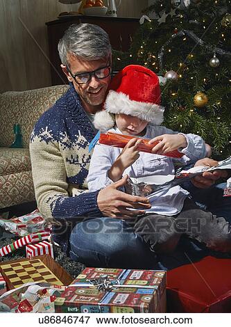 Father on sitting room floor opening christmas gifts with son View Large Photo Image Stock Photo - Father on sitting room floor opening christmas gifts with son. Fotosearch