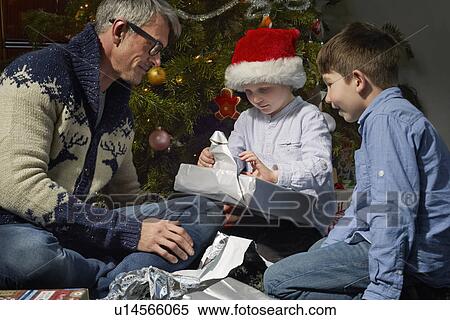 Father on sitting room floor opening christmas gifts with two sons View Large Photo Image Stock Photography - Father on sitting room floor opening christmas gifts with two sons. Fotosearch