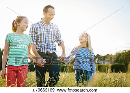 Stock Photo - Father on walk with two daughters, holding hands. Fotosearch