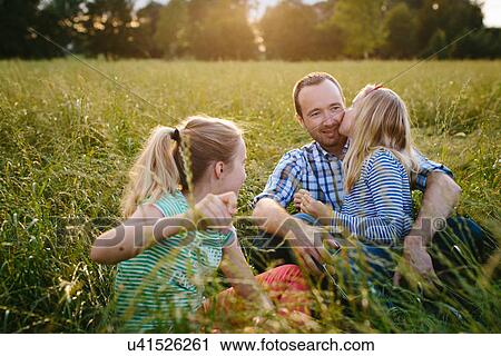 Father sitting in field with two daughters View Large Photo Image Stock Image - Father sitting in field with two daughters. Fotosearch