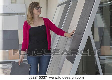 Stock Photo - Female customer admiring floor tile display in hardware store. Fotosearch