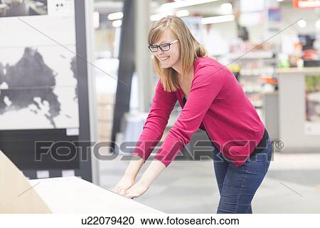 Stock Image - Female customer opening chest of drawers in hardware store. Fotosearch