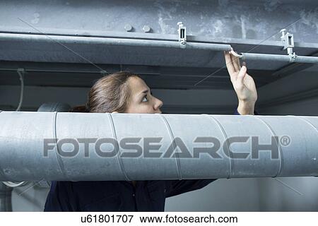 Female engineer looking up at industrial piping in factory View Large Photo Image Stock Photo - Female engineer looking up at industrial piping in factory. Fotosearch