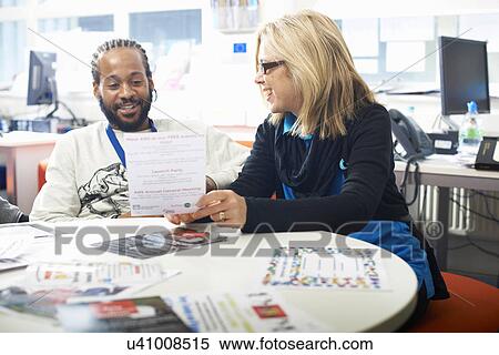 Stock Photography - Female lecturer and college student having informal discussion in classroom. Fotosearch
