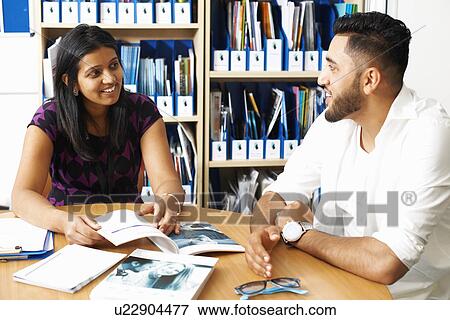 Stock Photo - Female lecturer having tutorial with male student in college classroom. Fotosearch
