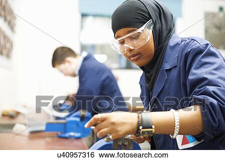 Stock Photograph - Female student using vice grip in college workshop. Fotosearch