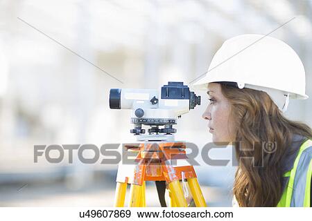 Female surveyor looking through level on construction site View Large Photo Image Stock Photo - Female surveyor looking through level on construction site. Fotosearch