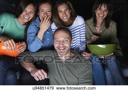 Five adult friends laughing and watching TV with snack bowls View Large Photo Image Stock Photo - Five adult friends laughing and watching TV with snack bowls. Fotosearch