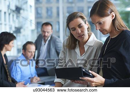 Stock Image - Five businesswomen and men busy working in office. Fotosearch