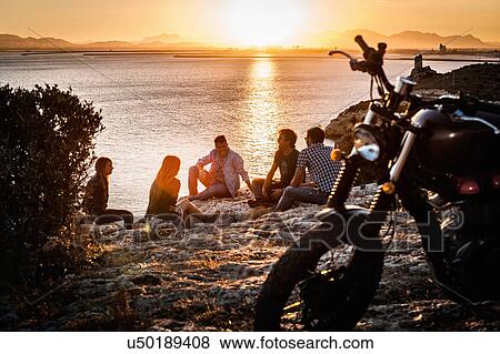 Five motorcycling friends taking a break on coast at sunset, Cagliari, Sardinia, Italy View Large Photo Image Stock Photo - Five motorcycling friends taking a break on coast at sunset, Cagliari, Sardinia, Italy. Fotosearch