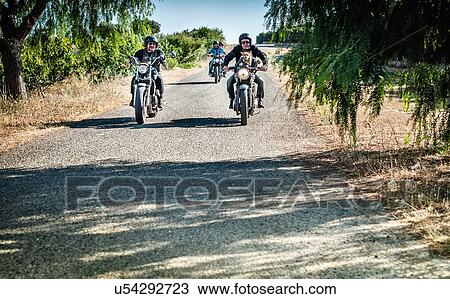 Stock Image - Four friends and one dog riding motorcycles on rural road, Cagliari, Sardinia, Italy. Fotosearch