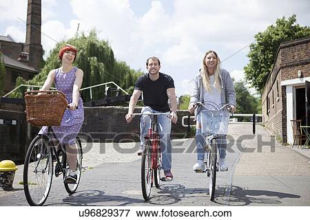 Friends riding bike along canal, East London, UK View Large Photo Image Stock Photo - Friends riding bike along canal, East London, UK. Fotosearch