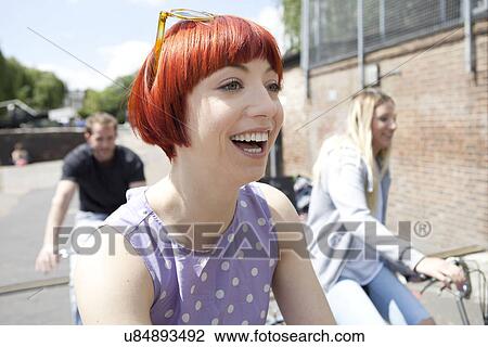 Stock Image - Friends riding bikes along canal. Fotosearch