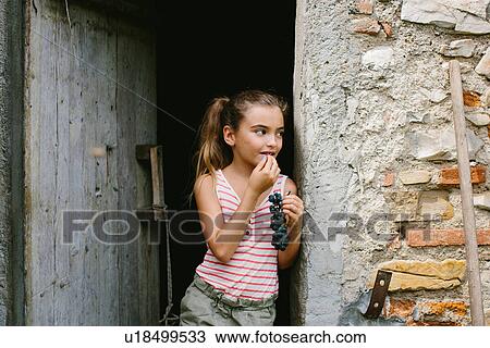 Girl eating grapes in barn doorway View Large Photo Image Stock Image - Girl eating grapes in barn doorway. Fotosearch
