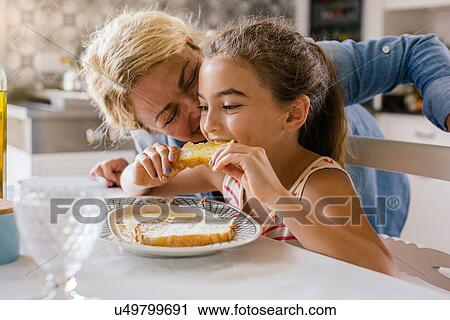Stock Image - Girl eating toast with grandmother. Fotosearch