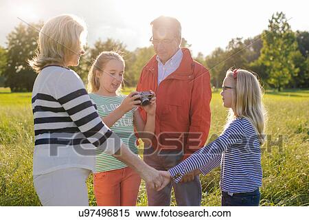 Girl holding camera with grandparents and sister View Large Photo Image Stock Photography - Girl holding camera with grandparents and sister. Fotosearch
