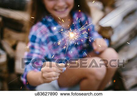 Stock Image - Girl holding sparkler, close up. Fotosearch