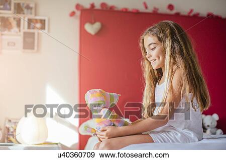 Girl in bedroom holding soft toy View Large Photo Image Stock Photo - Girl in bedroom holding soft toy. Fotosearch