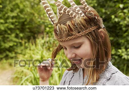 Girl in feather headdress playing with hair View Large Photo Image Stock Image - Girl in feather headdress playing with hair. Fotosearch