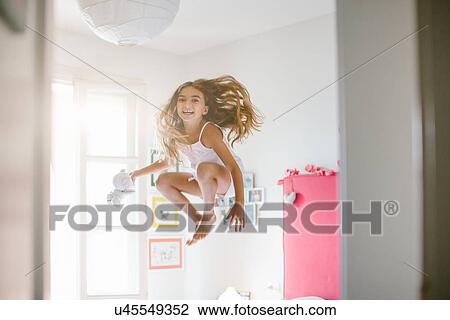 Girl jumping mid air in bedroom View Large Photo Image Stock Image - Girl jumping mid air in bedroom. Fotosearch