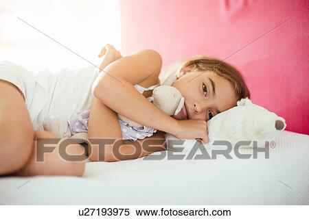 Girl lying on bed with soft toy View Large Photo Image Stock Photography - Girl lying on bed with soft toy. Fotosearch