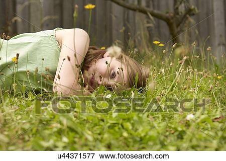 Girl lying on garden grass daydreaming View Large Photo Image Stock Photo - Girl lying on garden grass daydreaming. Fotosearch