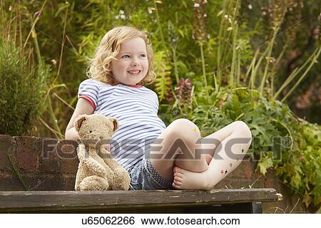 Girl on garden seat with teddy bear and star stickers on legs View Large Photo Image Stock Photograph - Girl on garden seat with teddy bear and star stickers on legs. Fotosearch