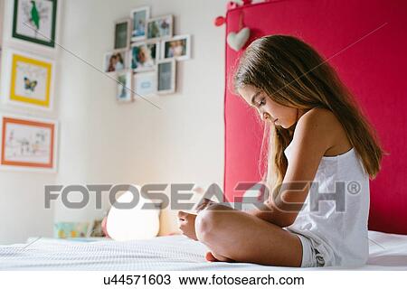 Girl sitting on bed, reading View Large Photo Image Stock Image - Girl sitting on bed, reading. Fotosearch