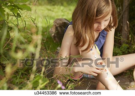 Girl sticking stars on legs in garden View Large Photo Image Stock Photograph - Girl sticking stars on legs in garden. Fotosearch