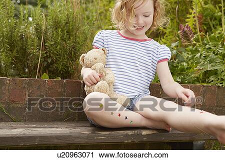 Girl sticking stars on legs on garden seat View Large Photo Image Stock Image - Girl sticking stars on legs on garden seat. Fotosearch