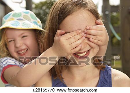 Girl with hands over her sisters eyes in garden View Large Photo Image Stock Image - Girl with hands over her sisters eyes in garden. Fotosearch