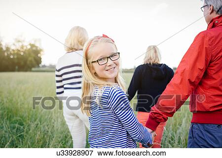 Granddaughter holding grandfather's hand in field View Large Photo Image Stock Photo - Granddaughter holding grandfather's hand in field. Fotosearch