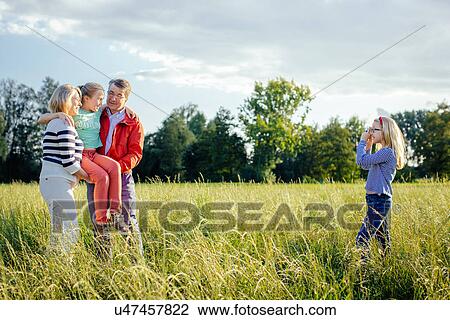 Granddaughter photographing grandparents and sister in field View Large Photo Image Stock Image - Granddaughter photographing grandparents and sister in field. Fotosearch