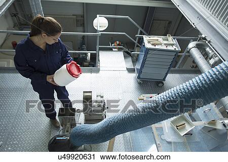 Stock Image - High angle view of factory worker reading instructions on plastic container. Fotosearch