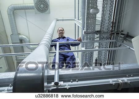 Low angle portrait of female engineer in factory View Large Photo Image Stock Photo - Low angle portrait of female engineer in factory. Fotosearch