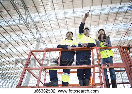 Low angle view of site managers and architect pointing from viewing platform on construction site View Large Photo Image Stock Image - Low angle view of site managers and architect pointing from viewing platform on construction site. Fotosearch