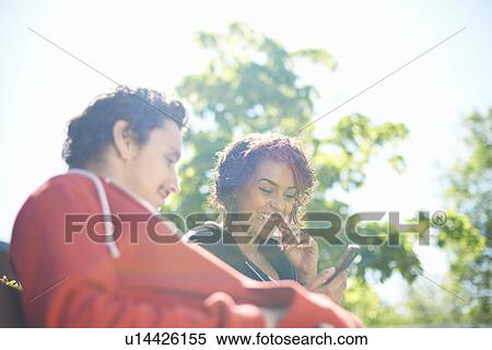 Male and female adult friends looking at text message on smartphone View Large Photo Image Stock Photography - Male and female adult friends looking at text message on smartphone. Fotosearch