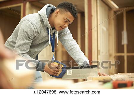 Stock Photo - Male college student using saw in woodworking workshop. Fotosearch