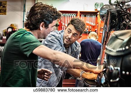 Male mechanics chatting in motorcycle workshop View Large Photo Image Stock Image - Male mechanics chatting in motorcycle workshop. Fotosearch