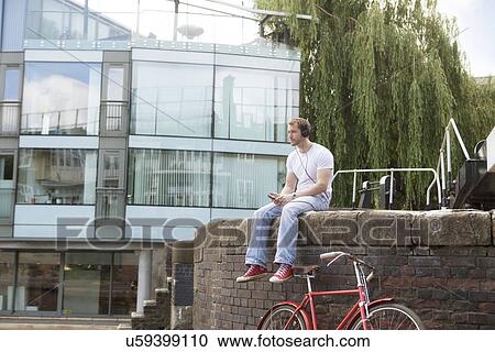 Man listening to music by canal, East London, UK View Large Photo Image Stock Image - Man listening to music by canal, East London, UK. Fotosearch