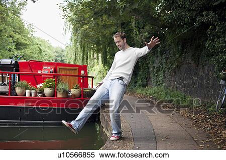 Stock Photography - Man pretending to fall into canal, East London, UK. Fotosearch
