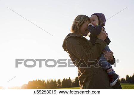 Mature mother and baby daughter in field at sunset View Large Photo Image Stock Photo - Mature mother and baby daughter in field at sunset. Fotosearch