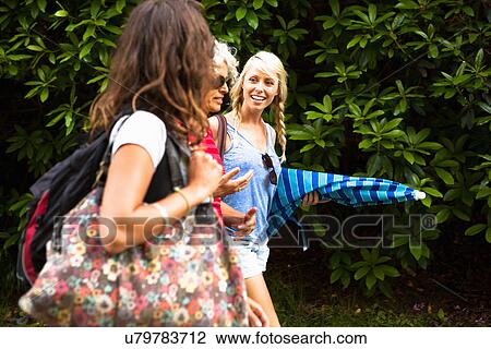 Stock Image - Mature mother and two daughters chatting and walking. Fotosearch