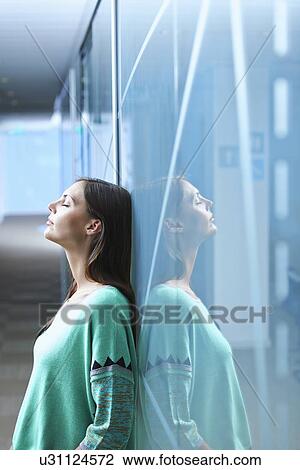 Mid adult businesswoman leaning against glass wall in office with eyes closed View Large Photo Image Stock Image - Mid adult businesswoman leaning against glass wall in office with eyes closed. Fotosearch